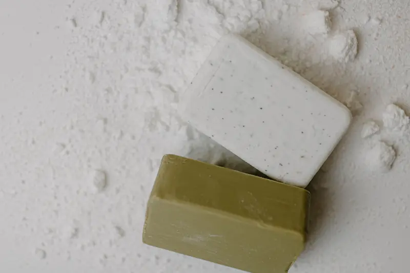 Close-up of two natural bar soaps on a white powdered surface, emphasizing hygiene