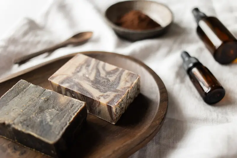 From above of fragrant handmade soap on wooden board near coffee organic scrub and bottles with aromatic oil