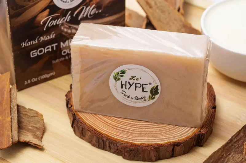 Close-up of handcrafted goat milk soap bar on a wooden slice, featuring natural ingredients and eco-friendly packaging