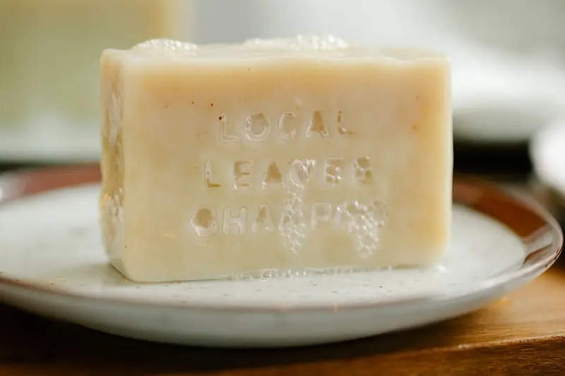 Rectangular shaped soap with letters covered with foam on plate on wooden table