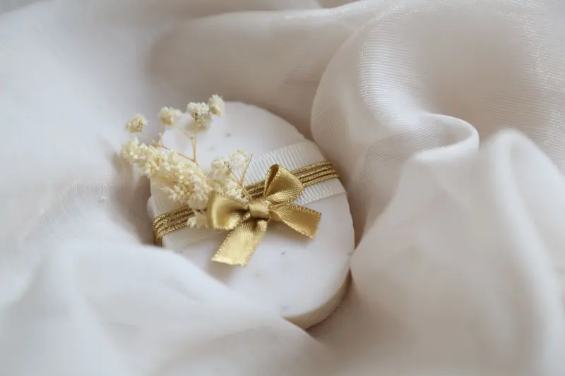A luxurious soap elegantly wrapped with a golden ribbon and delicate white flowers, perfect for gifting