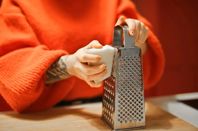 Person grating bar of soap with metal grater in kitchen, showcasing a hygiene concept
