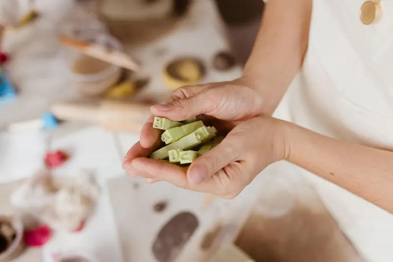Close-up of a woman holding handmade green soap bars in an arts and crafts setting