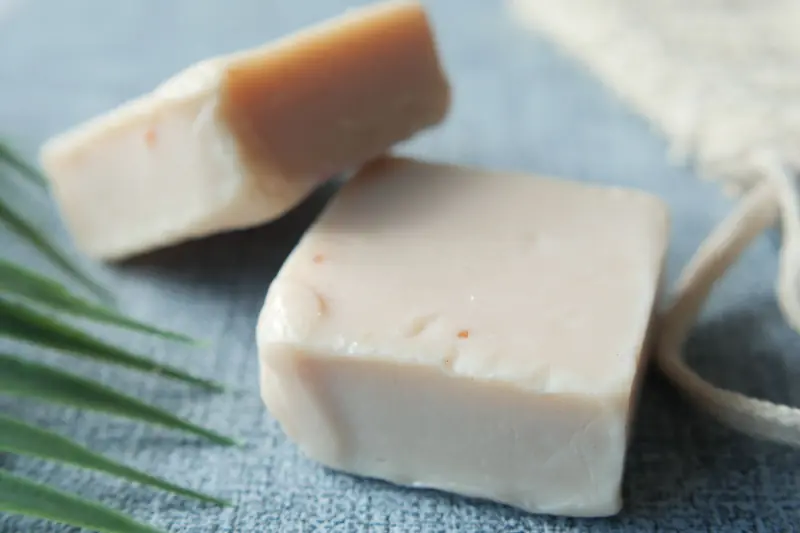 Two blocks of natural handmade soap on a textured surface, perfect for personal care stocks