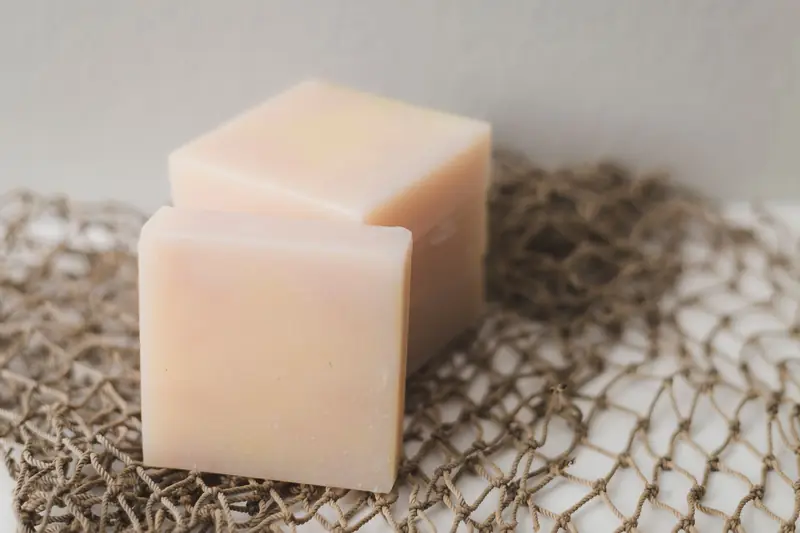 Two bars of natural handmade soap placed on a rustic netting backdrop, perfect for a spa theme