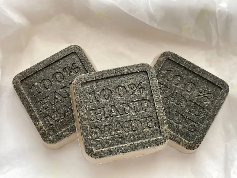 Close-up of three handmade soap bars with '100% Hand Made' inscription